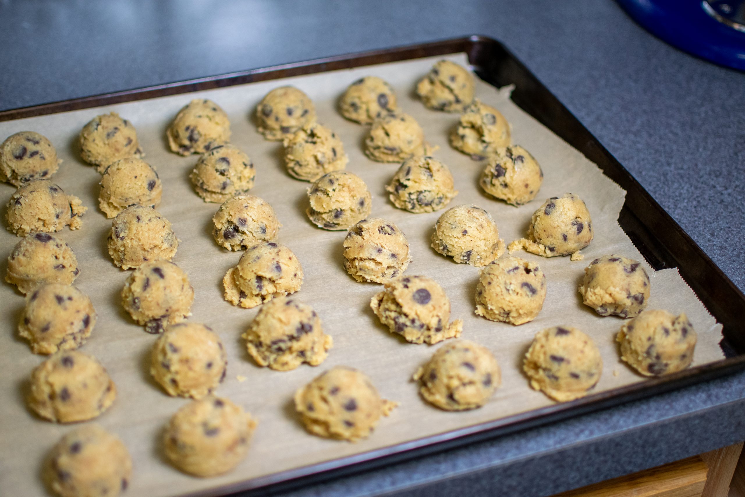 portioned chocolate chip cookie dough on a parchment-lined tray