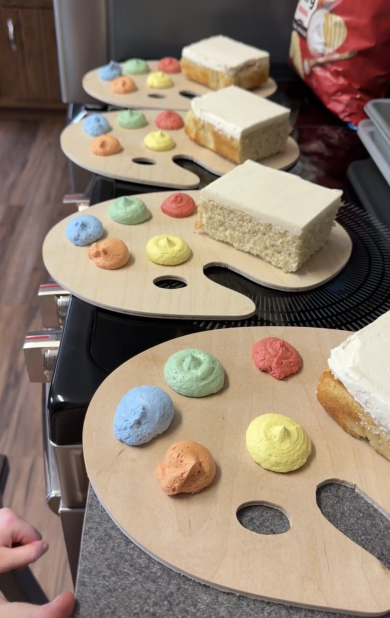 Homemade wooden artist palettes holding vanilla cake and colored buttercream