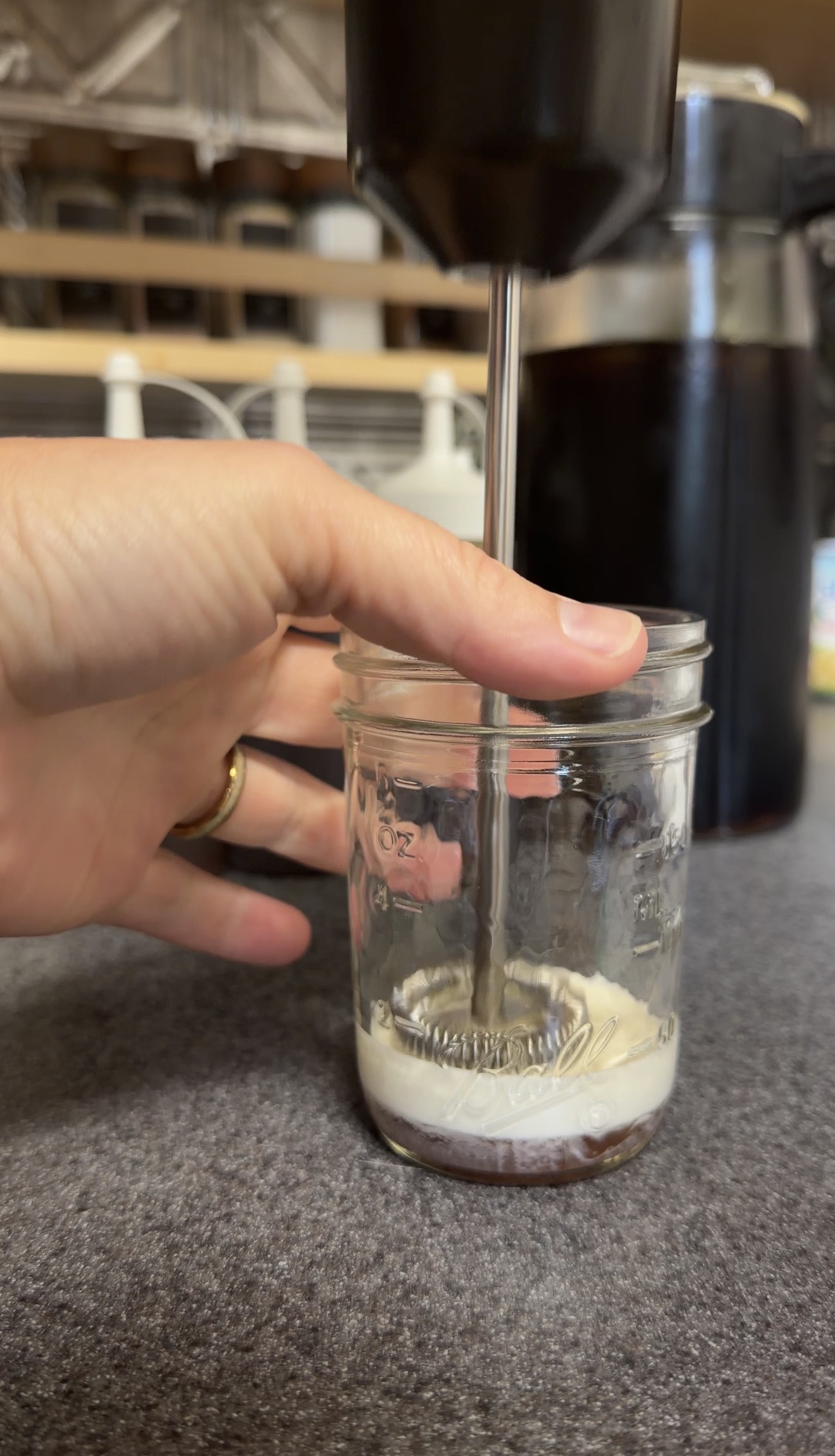Frothing cream and graham cracker syrup for homemade cold foam in a small glass jar.