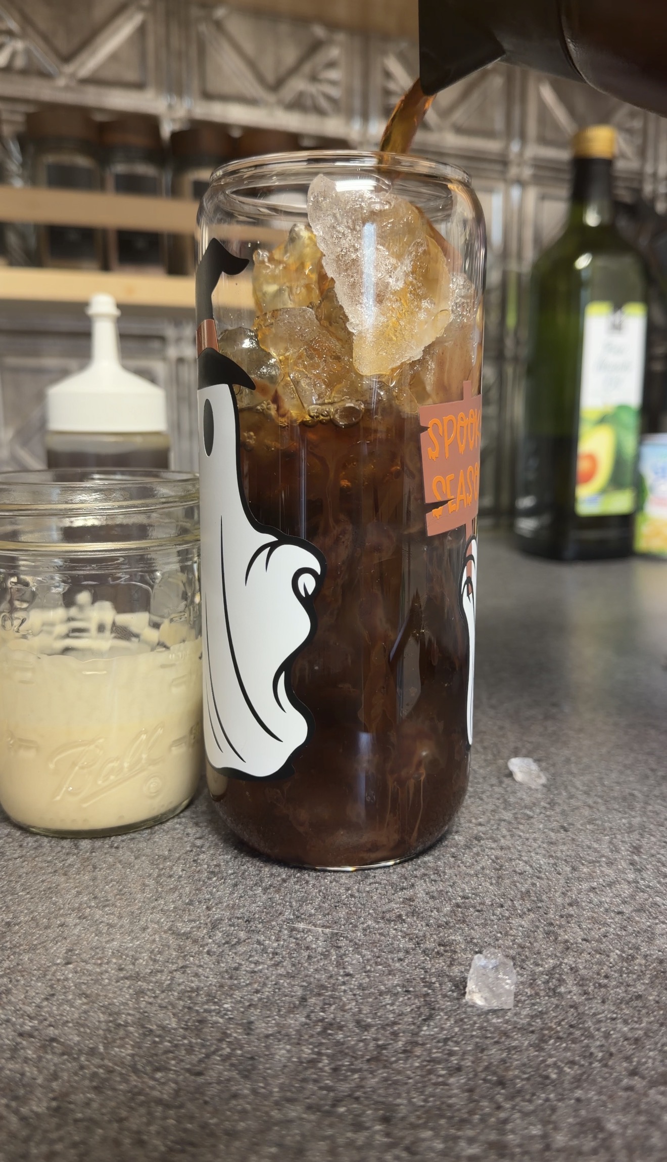 Fresh iced coffee pouring over chocolate syrup and ice for S’mores iced coffee.
