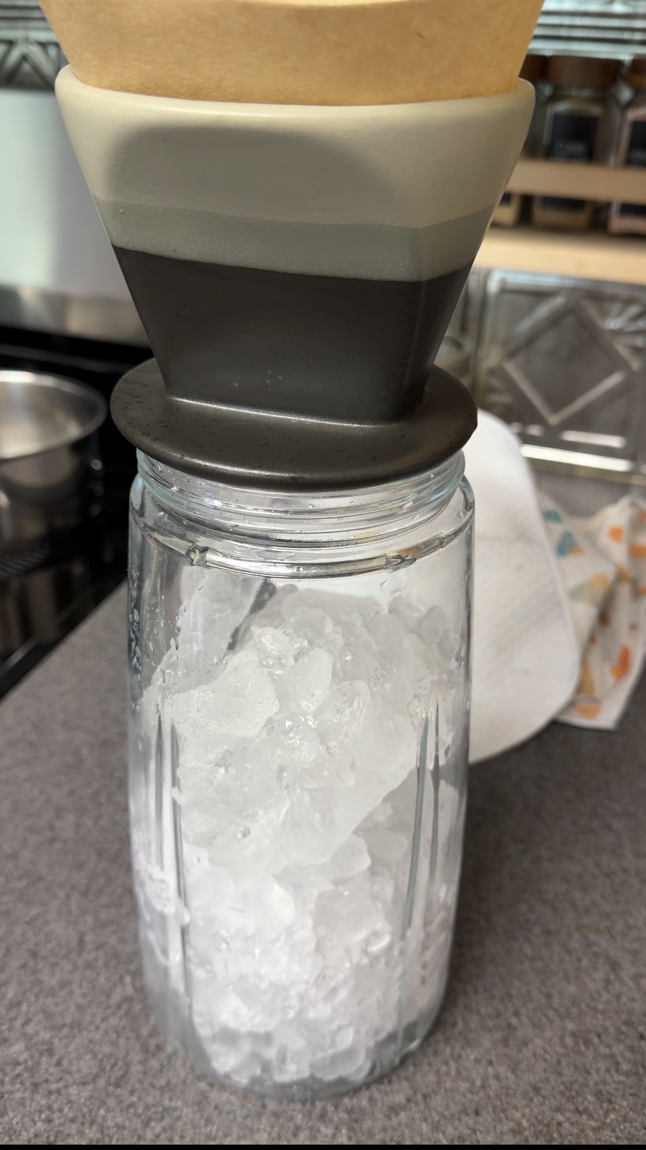 Pour-over brewer positioned above a pitcher filled about three-quarters full with ice.