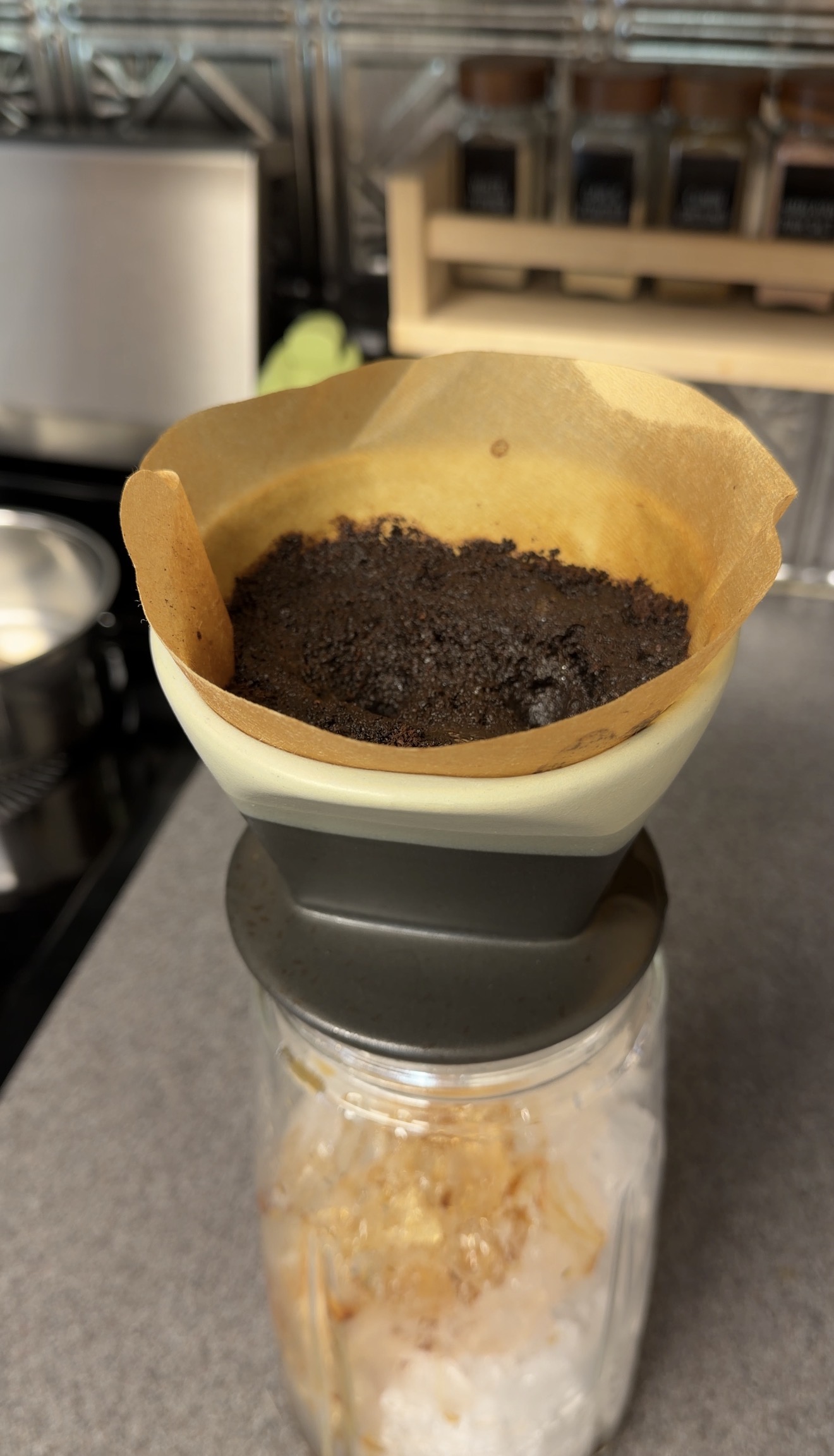 Evenly wetted coffee grounds in a pour-over filter above an ice-filled pitcher.