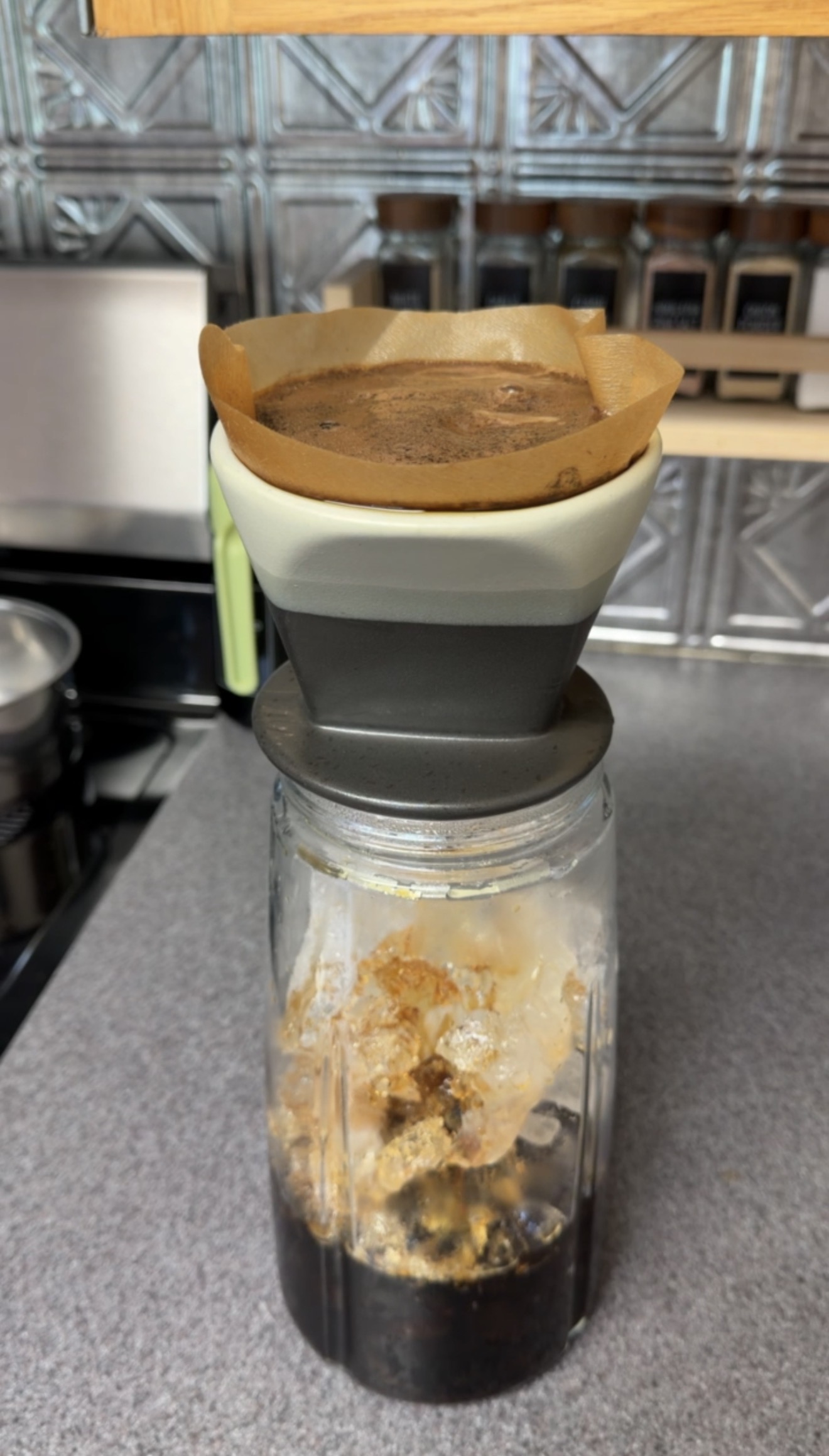 Coffee brewing through a pour-over filter directly into a pitcher of ice.